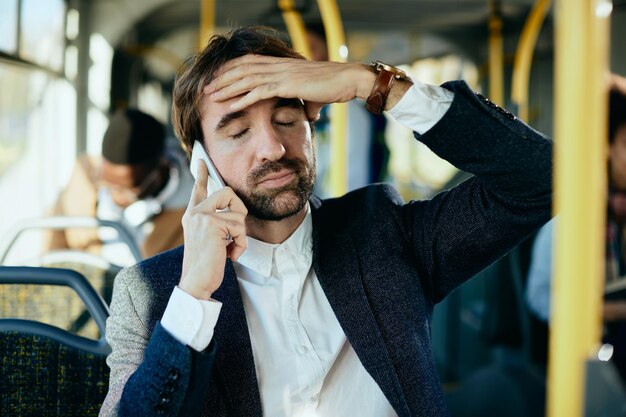 Empresario disgustado recibiendo malas noticias por teléfono mientras viaja en autobús