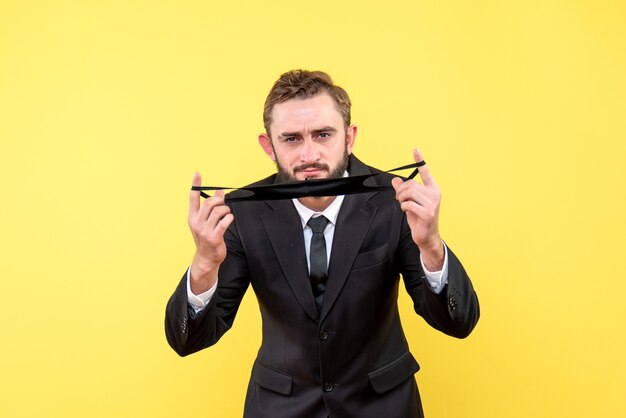 Empresario doblando y sosteniendo su máscara facial con los dedos en amarillo