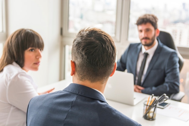 Empresario y empresaria sentado frente a gerente en el lugar de trabajo