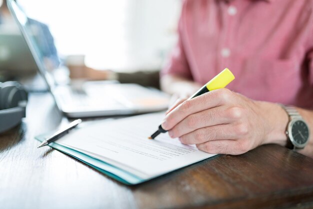 Empresario escribiendo en el documento con rotulador en el escritorio en el lugar de trabajo