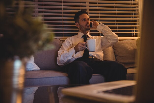 Empresario hablando por teléfono móvil mientras toma un café