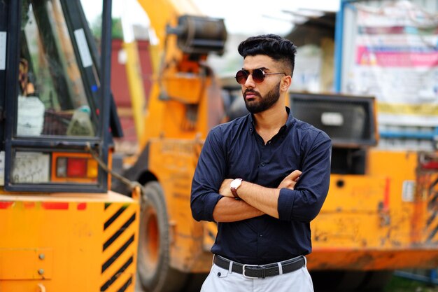 Empresario indio con una camisa negra con un tractor al fondo