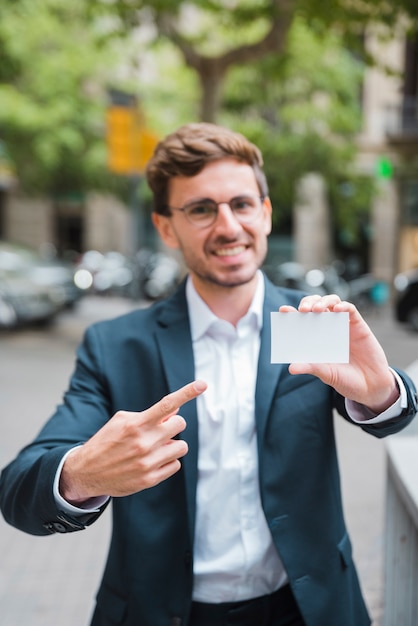 Empresario joven desenfocado apuntando su dedo hacia la tarjeta de visita