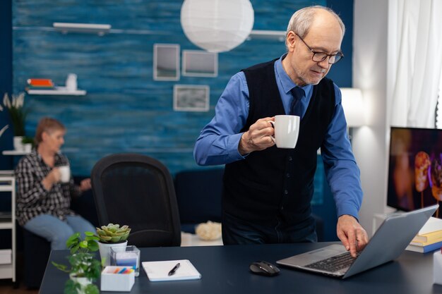 Empresario jubilado encender portátil disfrutando de una taza de café