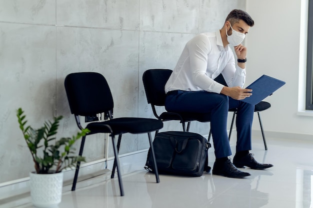 Empresario con mascarilla protectora mientras espera o entrevista de trabajo