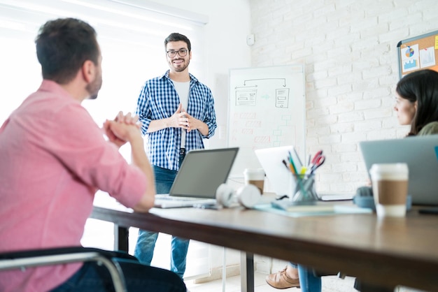 Empresario masculino confiado da una presentación a sus colegas mientras informa en una reunión en el lugar de trabajo
