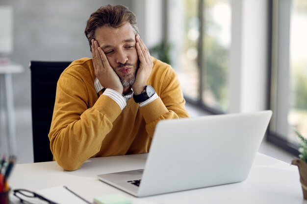 Empresario masculino enviando un beso durante una videollamada en la oficina