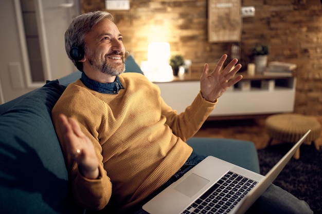 Empresario masculino feliz hablando durante una videollamada a través de una computadora portátil en casa