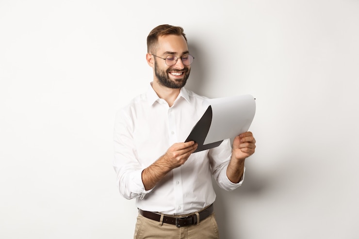 Foto gratuito empresario mirando satisfecho con los documentos, leyendo el informe y sonriendo, de pie