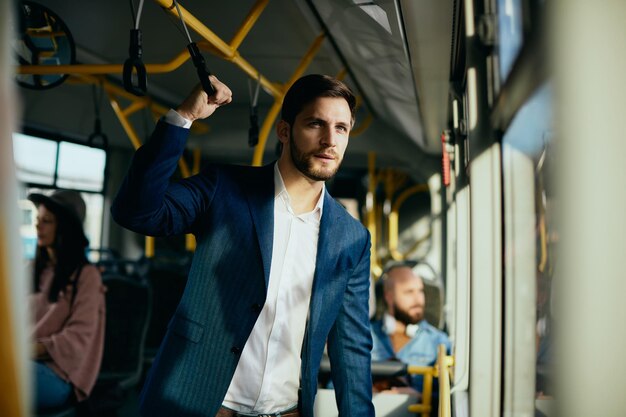 Empresario mirando por la ventana mientras viaja en autobús público