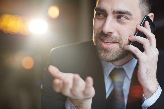 Empresario moderno sonriente hablando por teléfono inteligente