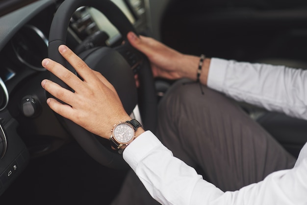 Un empresario monta su coche, se mueve sobre el volante. Mano con reloj.