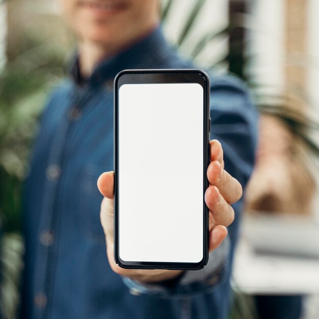 Empresario mostrando un teléfono de pantalla vacía