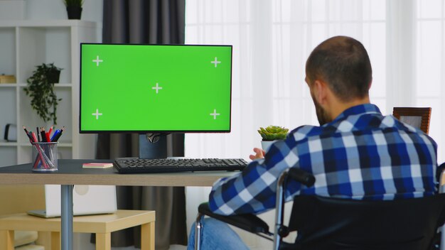 Empresario no válido saludando durante una videollamada en una computadora con pantalla verde.