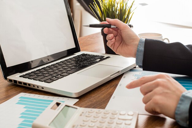 Empresario con ordenador portátil y calculadora en la oficina.