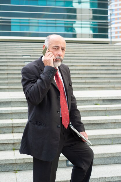 Empresario pensativo hablando por teléfono