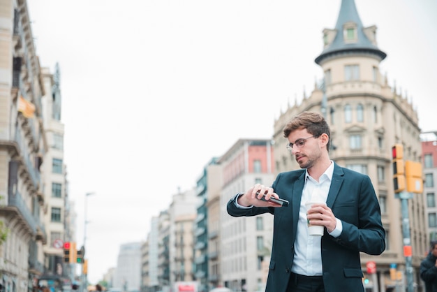 Foto gratuita empresario de pie en la calle de la ciudad viendo el tiempo en su reloj de pulsera