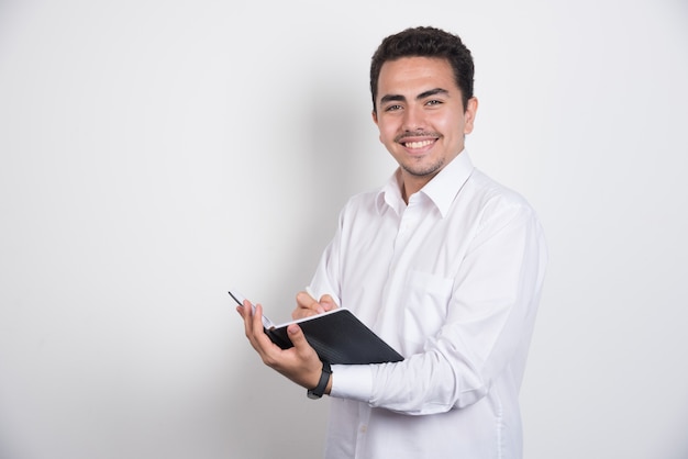 Empresario con portátil sonriendo sobre fondo blanco.