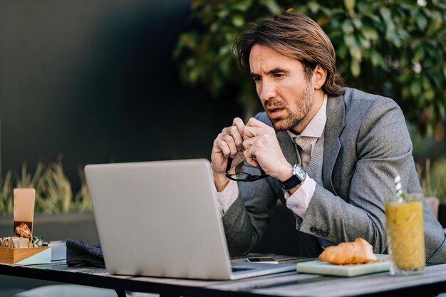 Empresario preocupado leyendo un correo electrónico en la computadora portátil mientras está sentado en un café