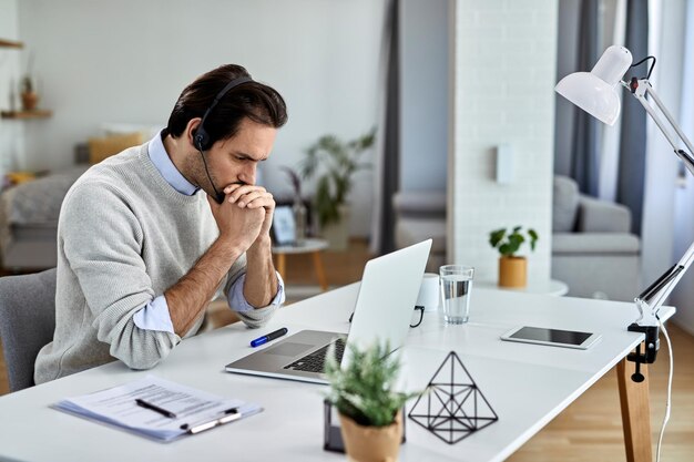 Empresario preocupado leyendo correo electrónico problemático en una computadora portátil mientras trabaja en casa