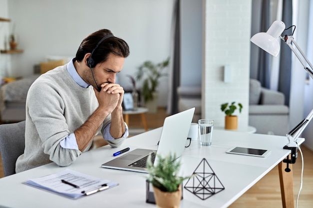 Empresario preocupado leyendo correo electrónico problemático en una computadora portátil mientras trabaja en casa