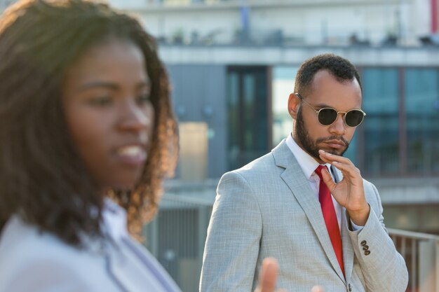 Empresario serio caminando afuera por su colega