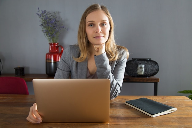 Empresario de sexo femenino joven contento que se sienta delante del ordenador portátil