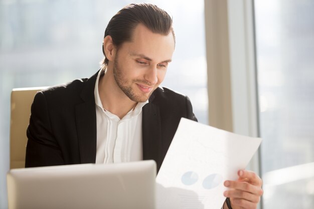 Empresario sonriente mirando informe financiero