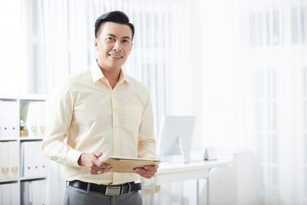 Empresario sonriente con tableta en oficina