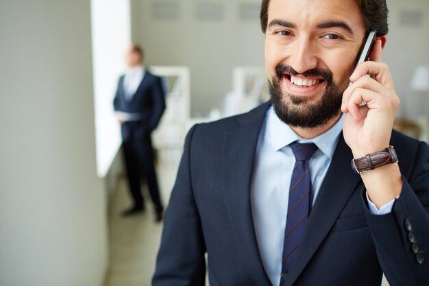 Empresario sonriente utilizando un teléfono móvil