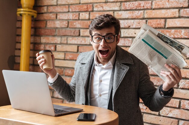 Empresario sorprendido en anteojos sentado junto a la mesa