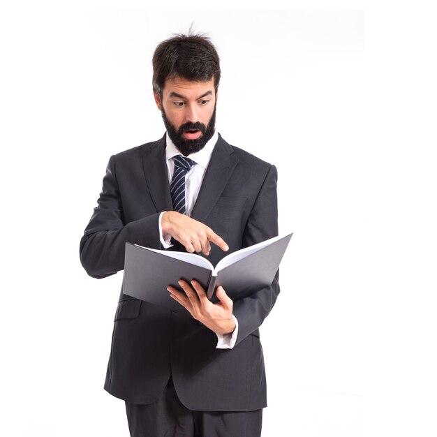 Empresario sorprendido leyendo un libro sobre fondo blanco