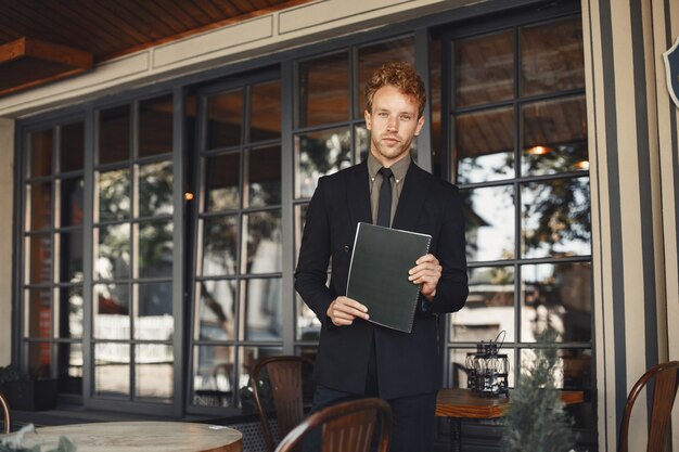 Empresario sosteniendo una carpeta en sus manos. Apuesto hombre de negocios confiado con traje de pie.