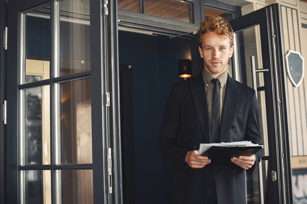 Empresario sosteniendo una carpeta en sus manos. Apuesto hombre de negocios confiado con traje de pie.