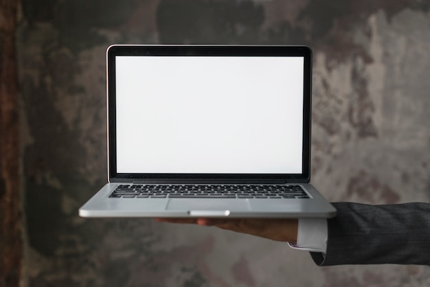 Empresario sosteniendo portátil con pantalla en blanco en blanco