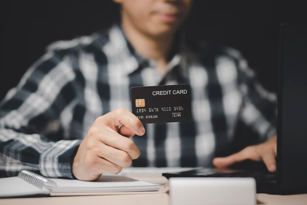 Empresario sosteniendo una tarjeta de crédito y usando una computadora portátil. concepto de compras en línea, banca y compras en línea en el hogar.