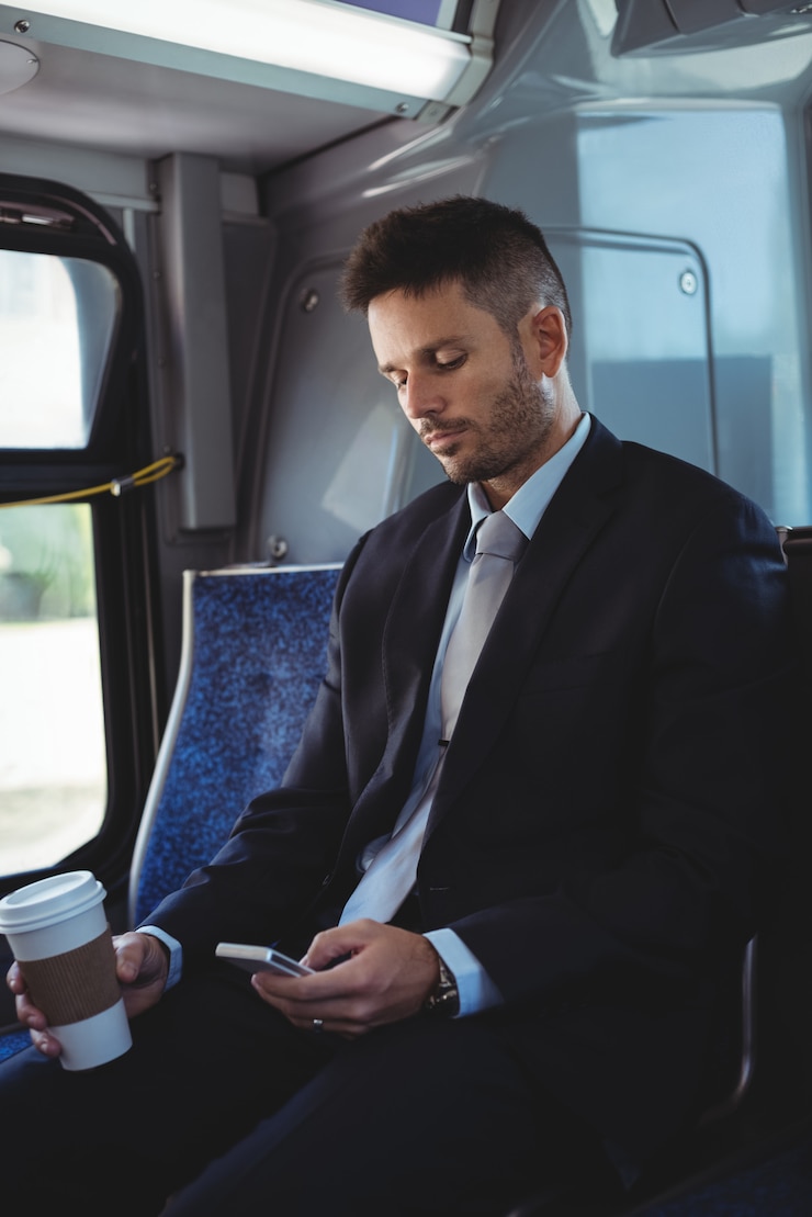 Foto gratuito empresario sosteniendo una taza de café desechable y utilizando el teléfono móvil
