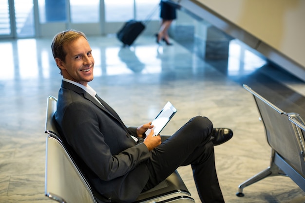 Foto gratuita empresario con tableta digital en la sala de espera de la terminal del aeropuerto