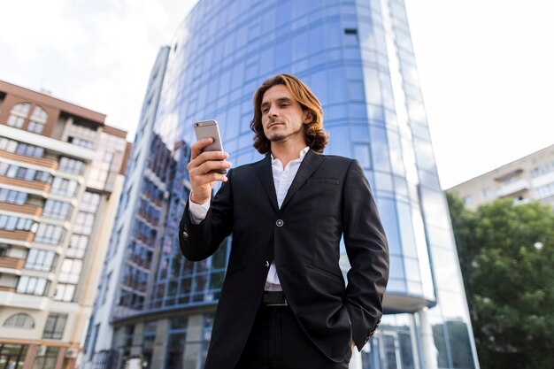 Empresario de tiro de ángulo bajo usando un teléfono