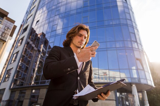 Empresario usando su teléfono frente a un edificio