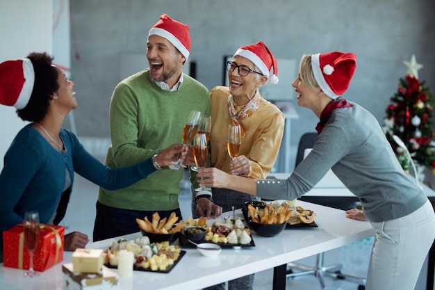 Foto gratuita empresarios alegres divirtiéndose y brindando con champán en la fiesta de navidad en la oficina