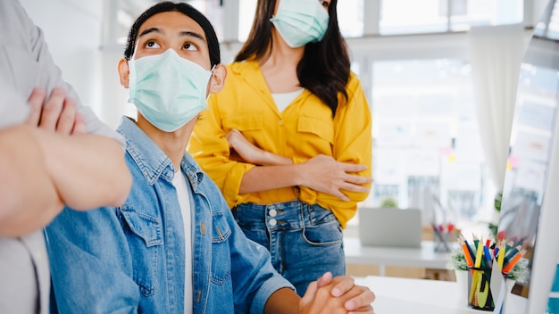 Foto gratuita empresarios de asia que utilizan reuniones de presentación por computadora para intercambiar ideas sobre nuevos colegas del proyecto y usan una mascarilla protectora en la nueva oficina normal. estilo de vida y trabajo después del coronavirus.