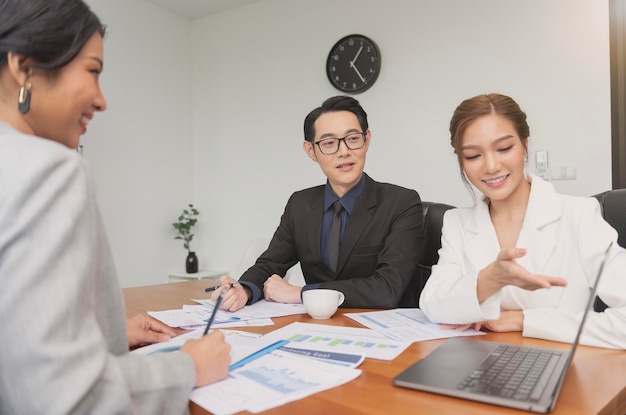 Empresarios asiáticos que se reúnen con corredores de bolsa mirando gráficos, índices y números en la computadora