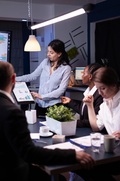 Empresarios diversos enfocados con exceso de trabajo que trabajan en la empresa de negocios que se encuentran en la sala de la oficina y piensan en la estrategia de marketing tarde en la noche