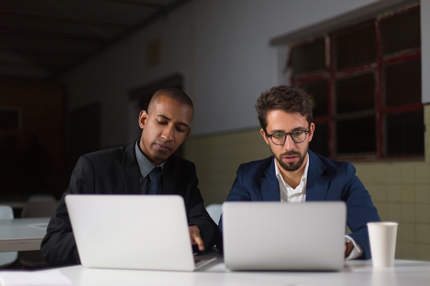 Empresarios enfocados usando computadoras portátiles