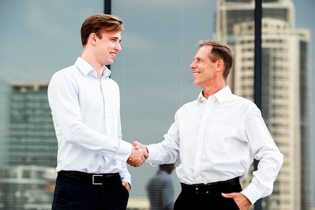 Empresarios estrecharme la mano cerca del edificio de cristal