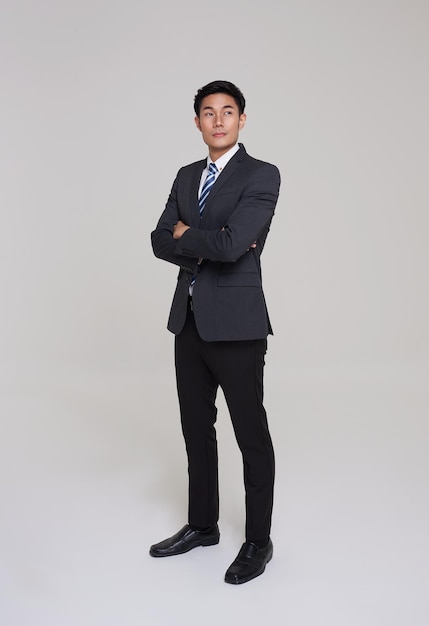 Empresarios guapos en el estudio Empresario asiático en traje gris confiado con los brazos cruzados
