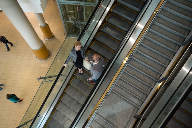 Los empresarios interactúan entre sí mientras bajan por la escalera mecánica