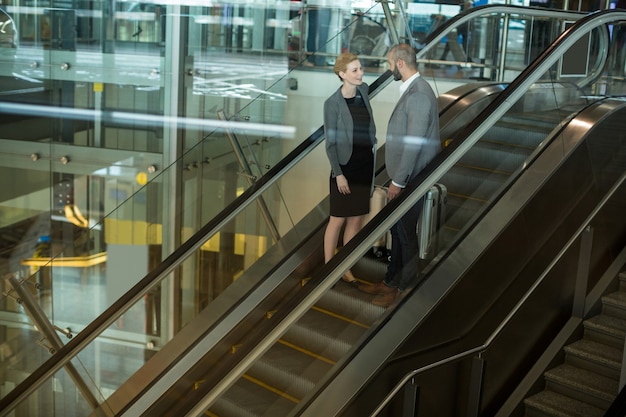 Empresarios interactuando entre sí mientras suben la escalera mecánica