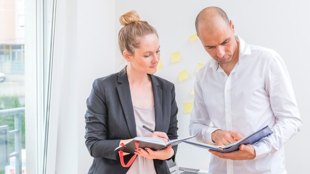 Empresarios masculinos y femeninos que miran horario en diario